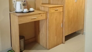 A small kitchenette with a wooden countertop, a coffee maker, and a trash bin. - Exotic Komodo Hotel (Labuan Bajo)