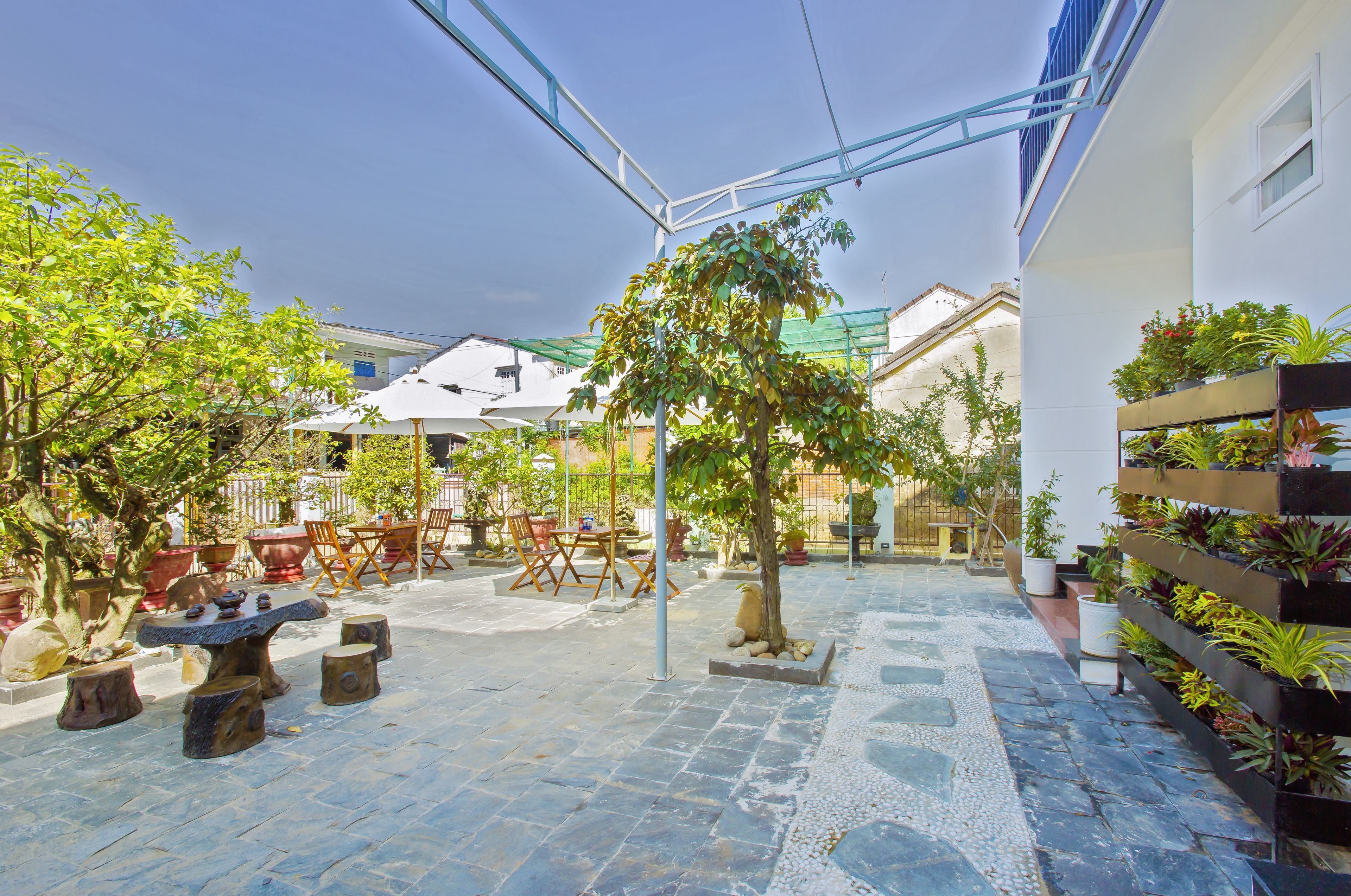 A courtyard with stone flooring, outdoor furniture, and potted plants.