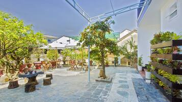 A courtyard with stone flooring, outdoor furniture, and potted plants.