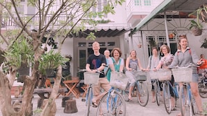 A group of people on bicycles in an outdoor setting with trees and a building in the background.