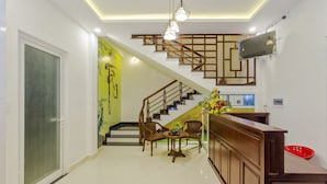 A modern interior with a staircase, wooden furniture, and a reception desk.