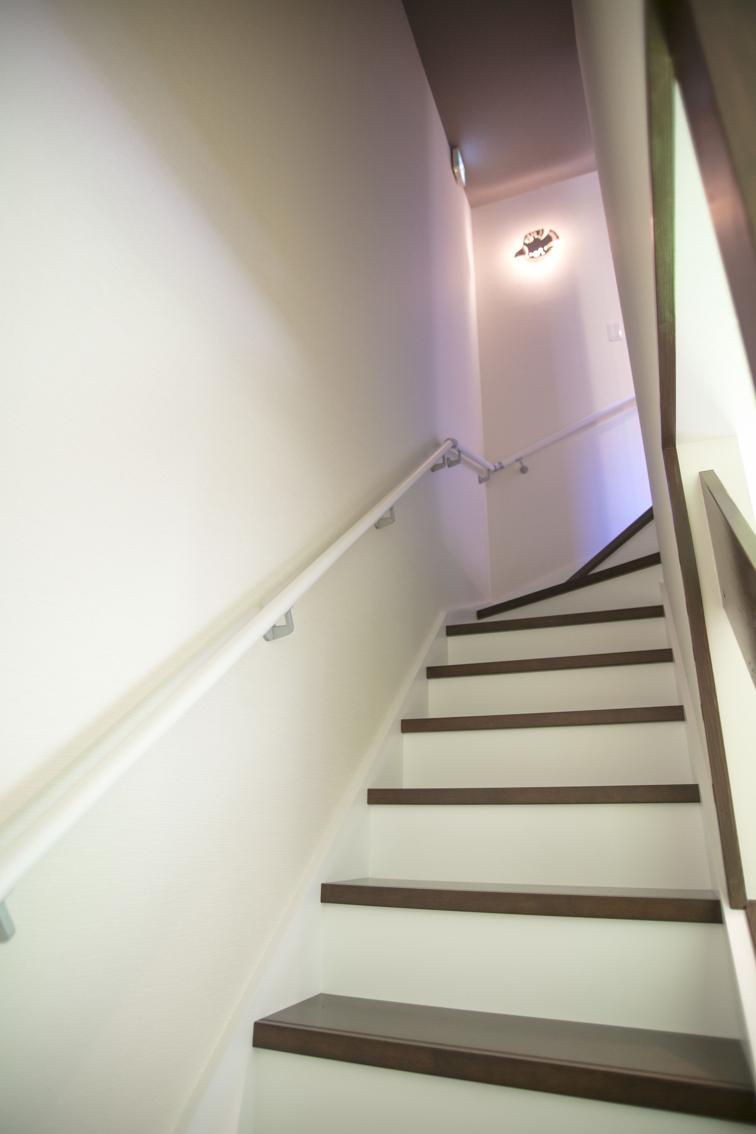 A staircase with white walls and wooden steps.