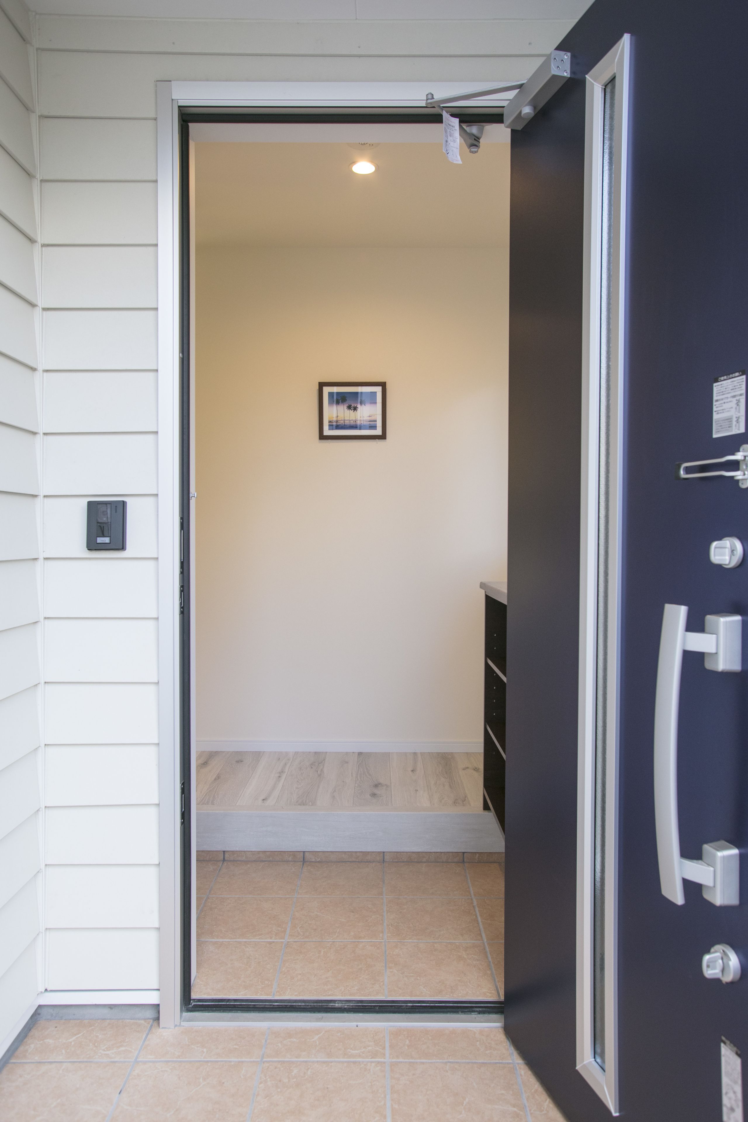 Una puerta que da a un cuarto con piso de baldosas y un cuadro en la pared.