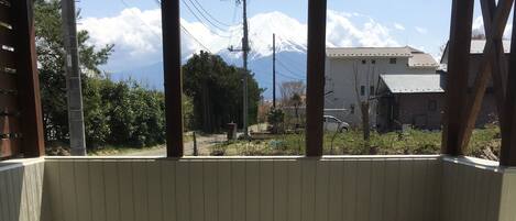 Un área de estar techada al aire libre con una mesa, sillas, un cubo de basura y vistas a una montaña nevada.