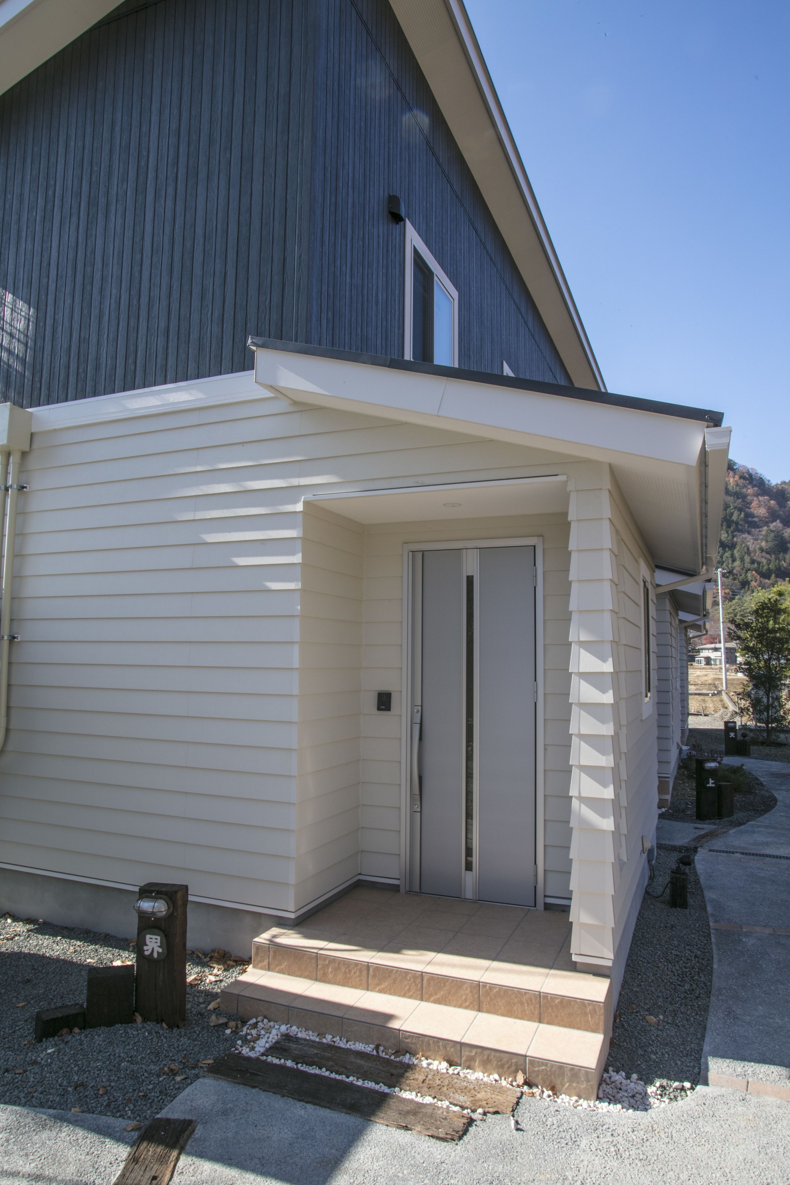 A modern building with a white exterior and a small entrance with steps leading up to a door.