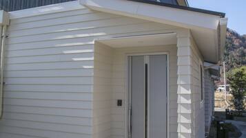A modern building with a white exterior and a small entrance with steps leading up to a door.
