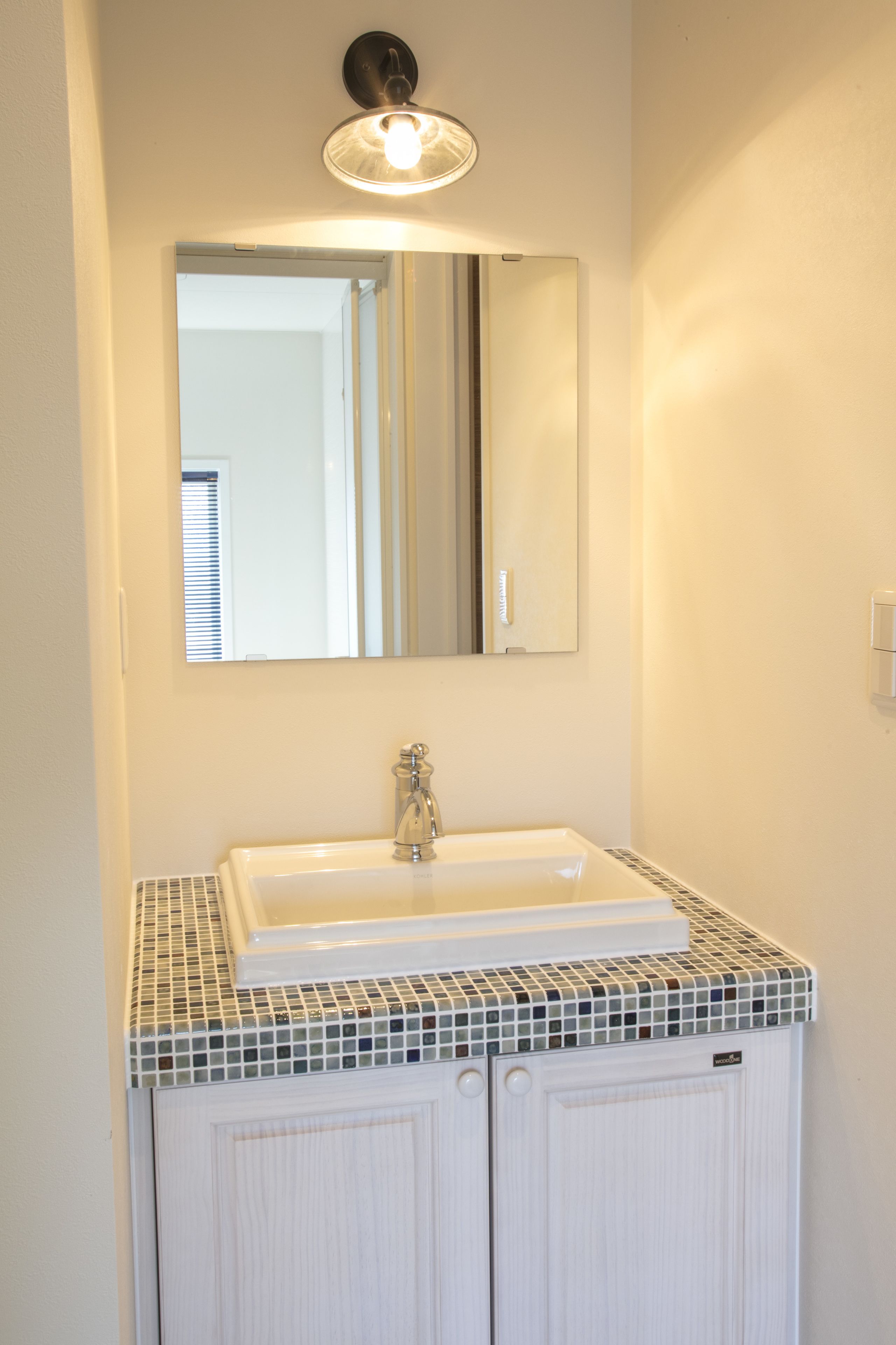 A bathroom with a white sink, a mirror above it, and a tiled countertop.