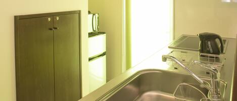 A compact kitchen with a stainless steel sink, a black range hood, and a small window.