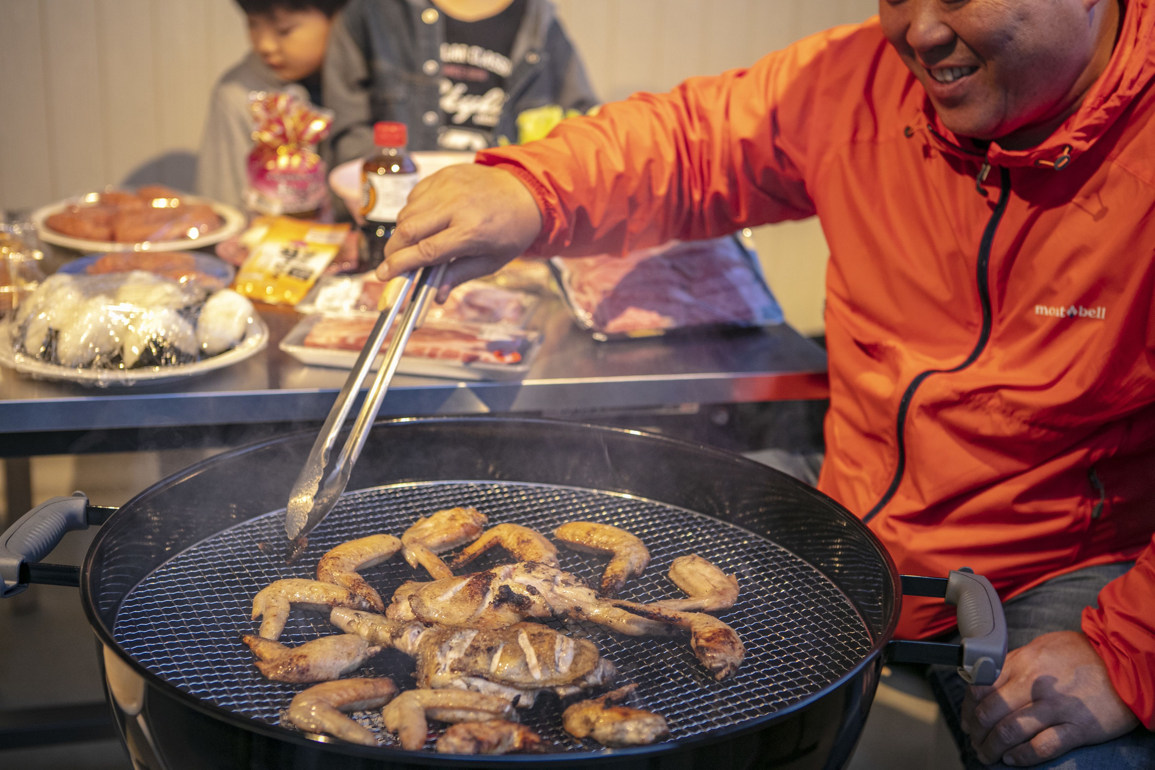 A person grilling sausages on a large outdoor grill.