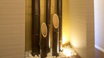 A bathroom with a bamboo installation, a mirror, and a light fixture.