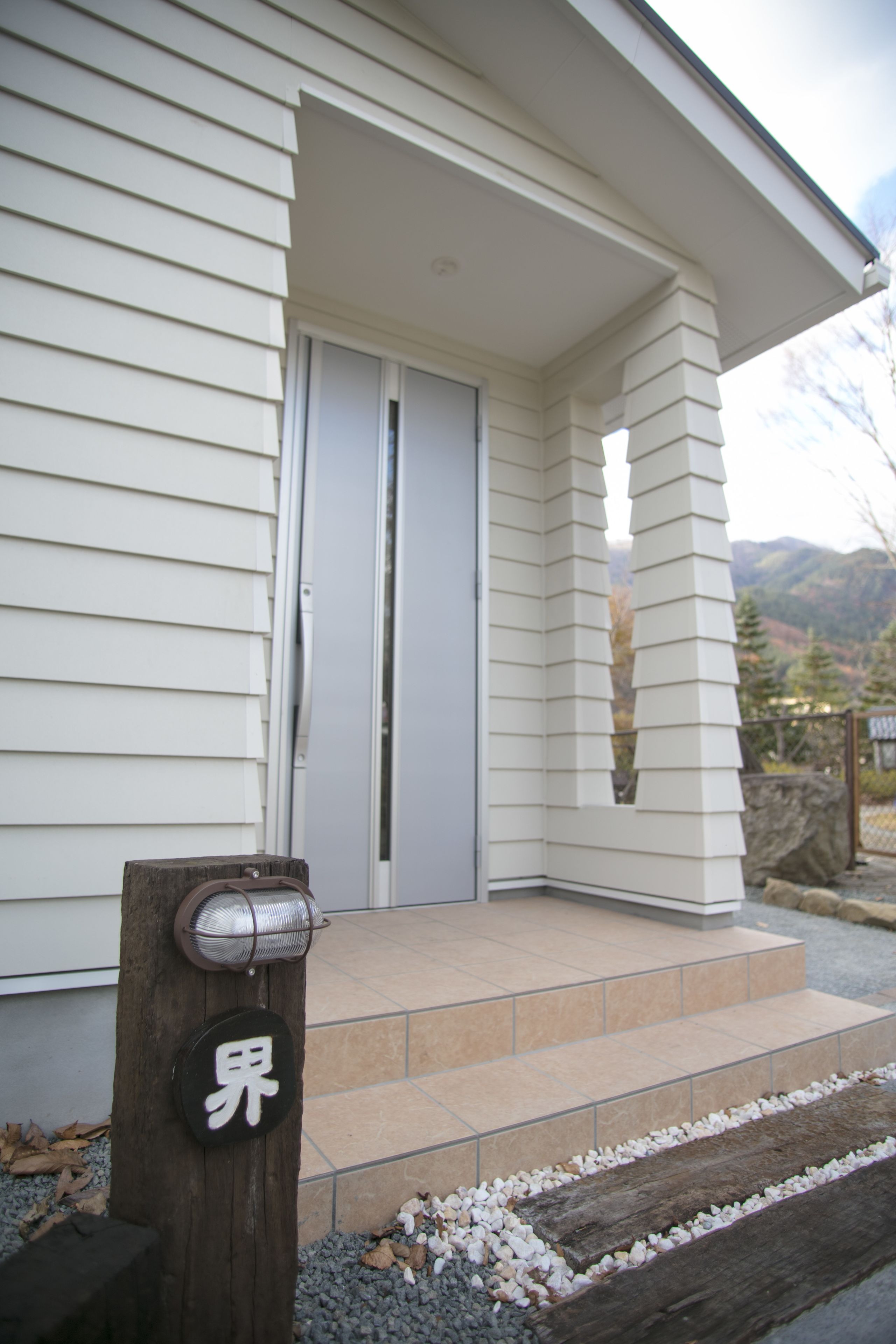 A house with a front door, a small porch, and a wooden post with a sign.