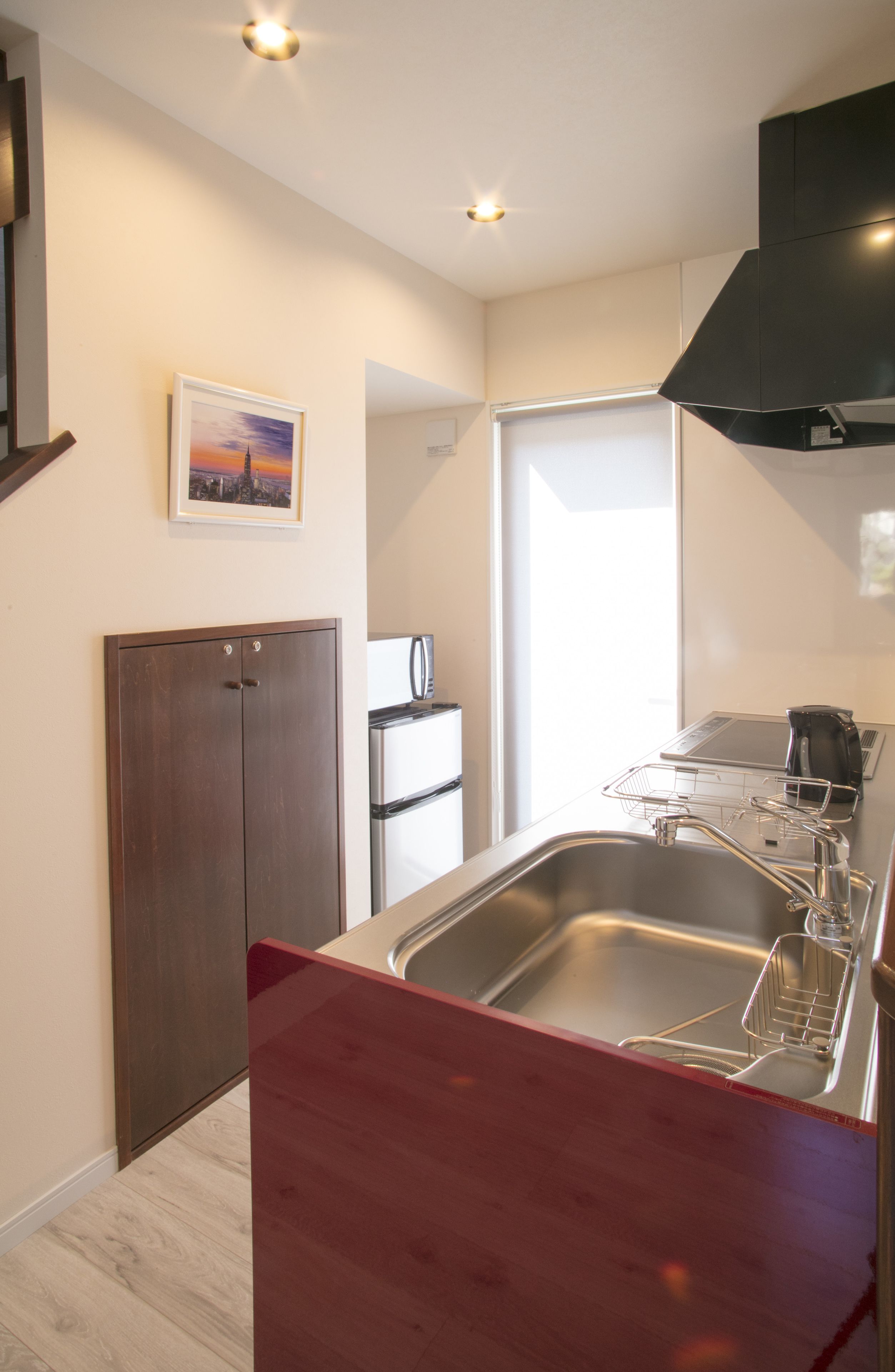 A modern kitchen with a stainless steel sink, a built-in oven, and a black range hood.