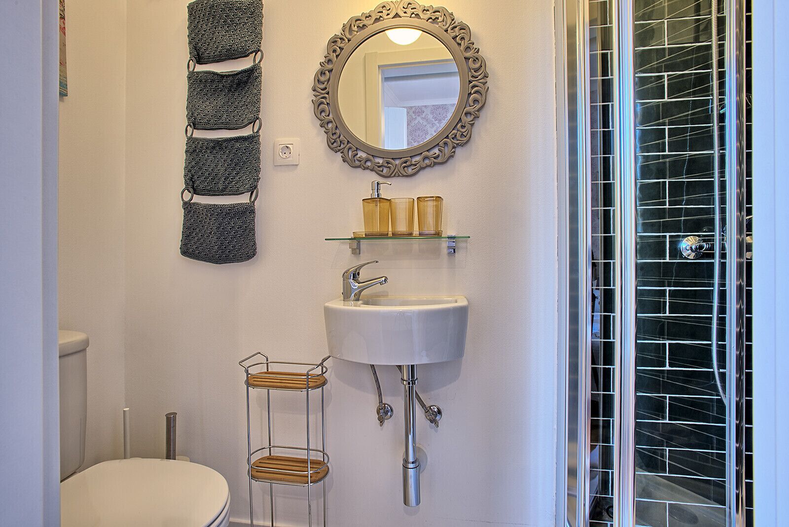 A bathroom with a white sink, a mirror with an ornate frame, and a glass shower enclosure.
