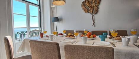 A dining area with a table set for breakfast, including plates, cups, and a fruit bowl.