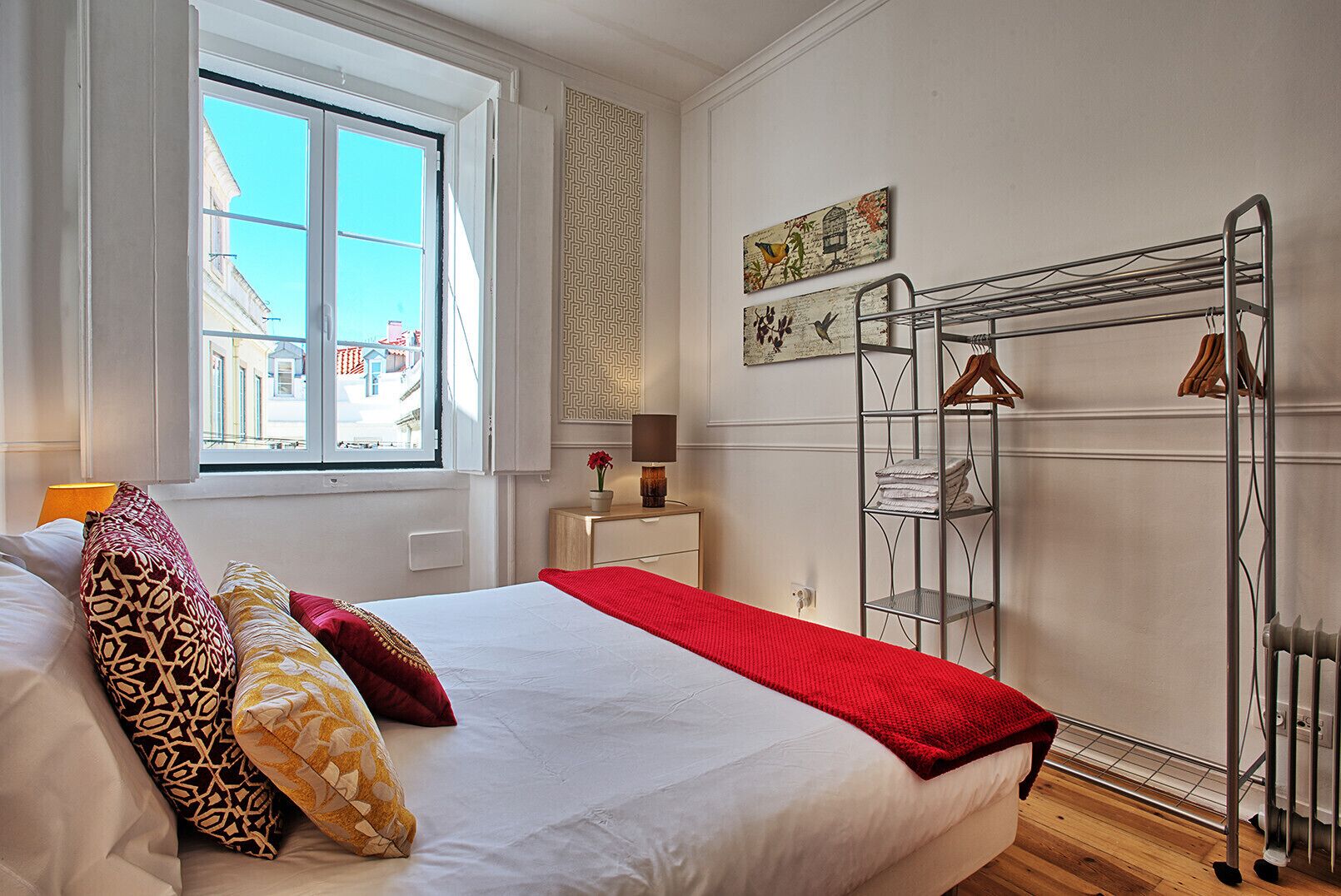 Una camera d'albergo con un letto, una finestra, un termosifone e un'asciugatrice a parete.