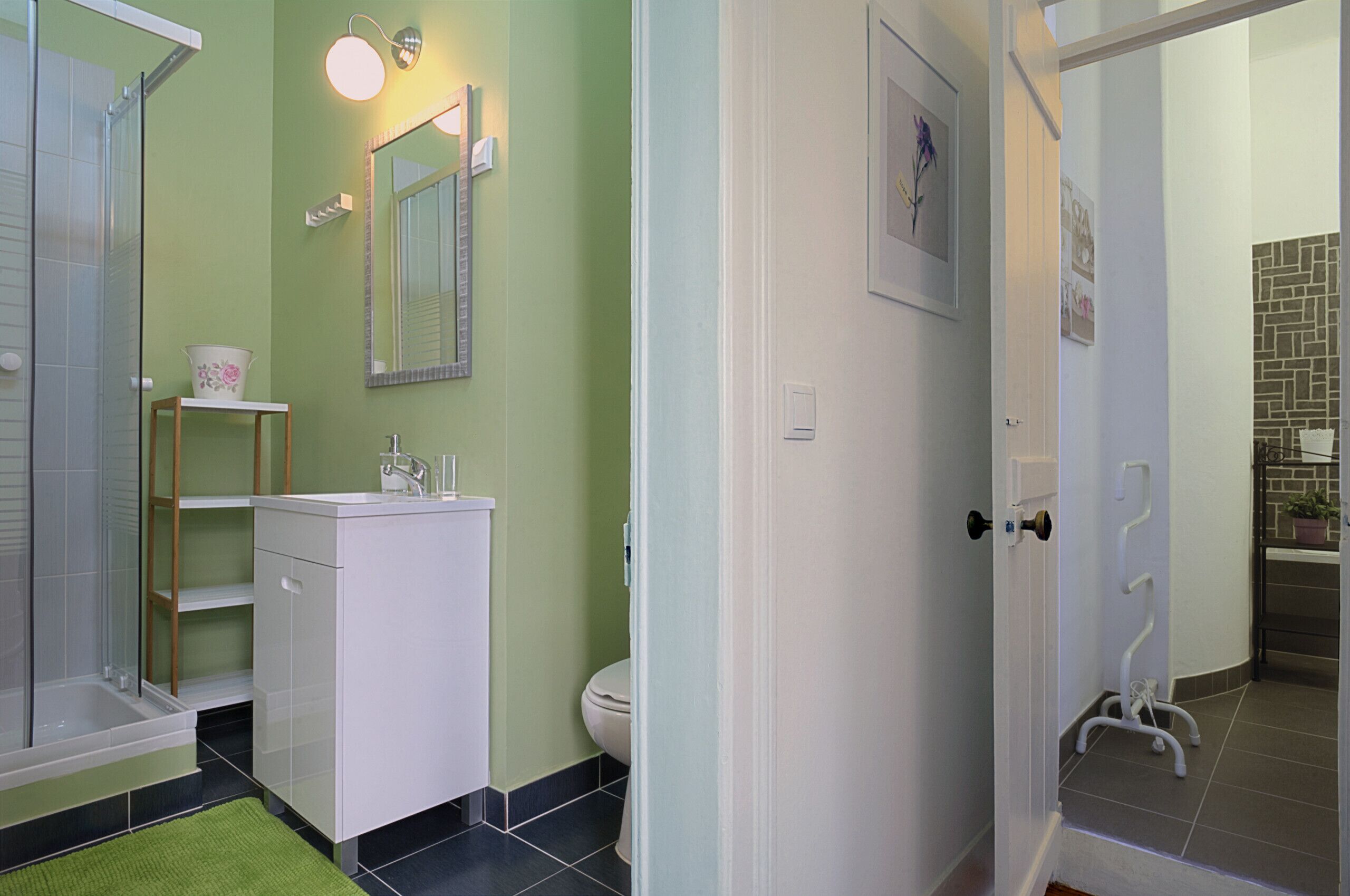 Casa de banho com parede verde, lavatório branco e zona de duche.