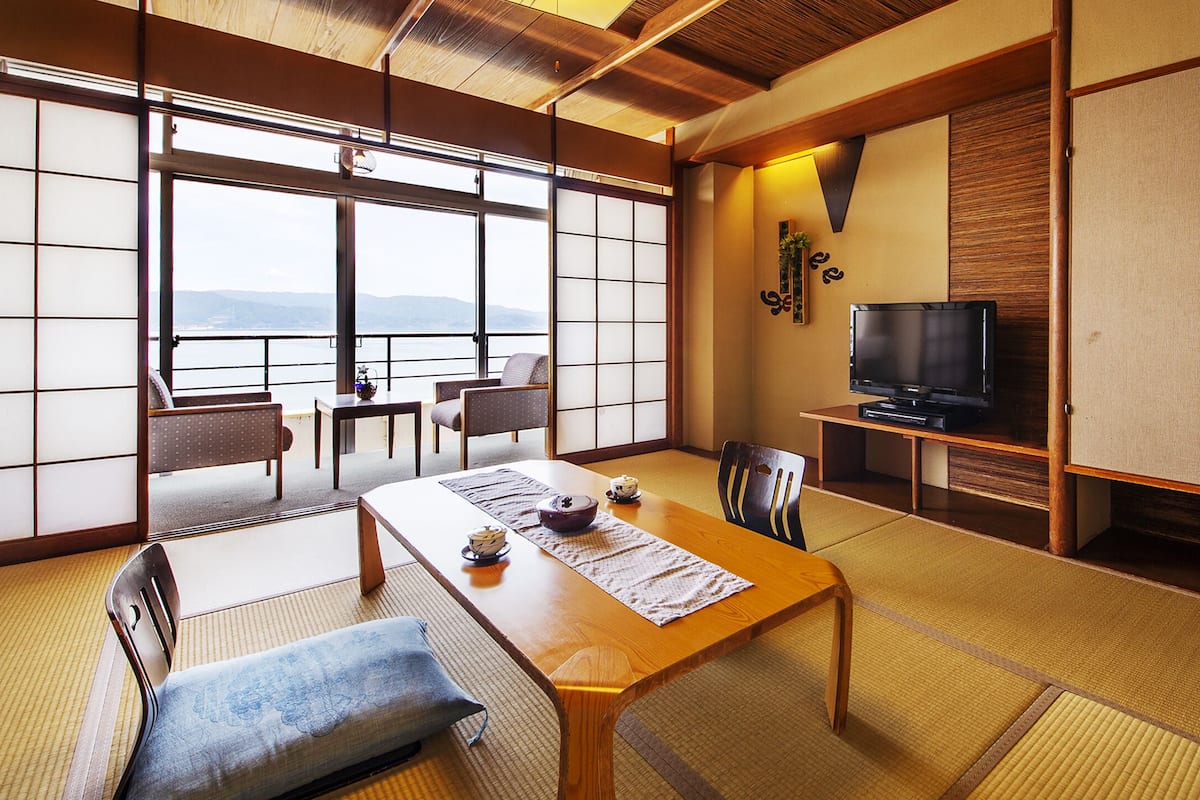 Una habitación japonesa tradicional con suelo de tatami, una mesa baja y un televisor.
