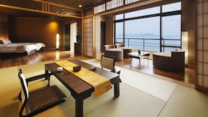 A modern hotel room with a large bed, a dining area with tatami mats, and a view of the sea. - Manpa Resort (Wakayama)
