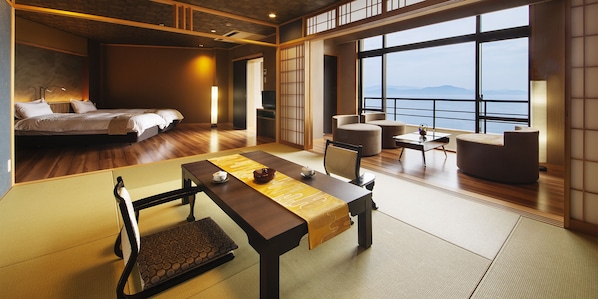 A modern hotel room with a large bed, a dining area with tatami mats, and a view of the sea. - Manpa Resort (Wakayama)