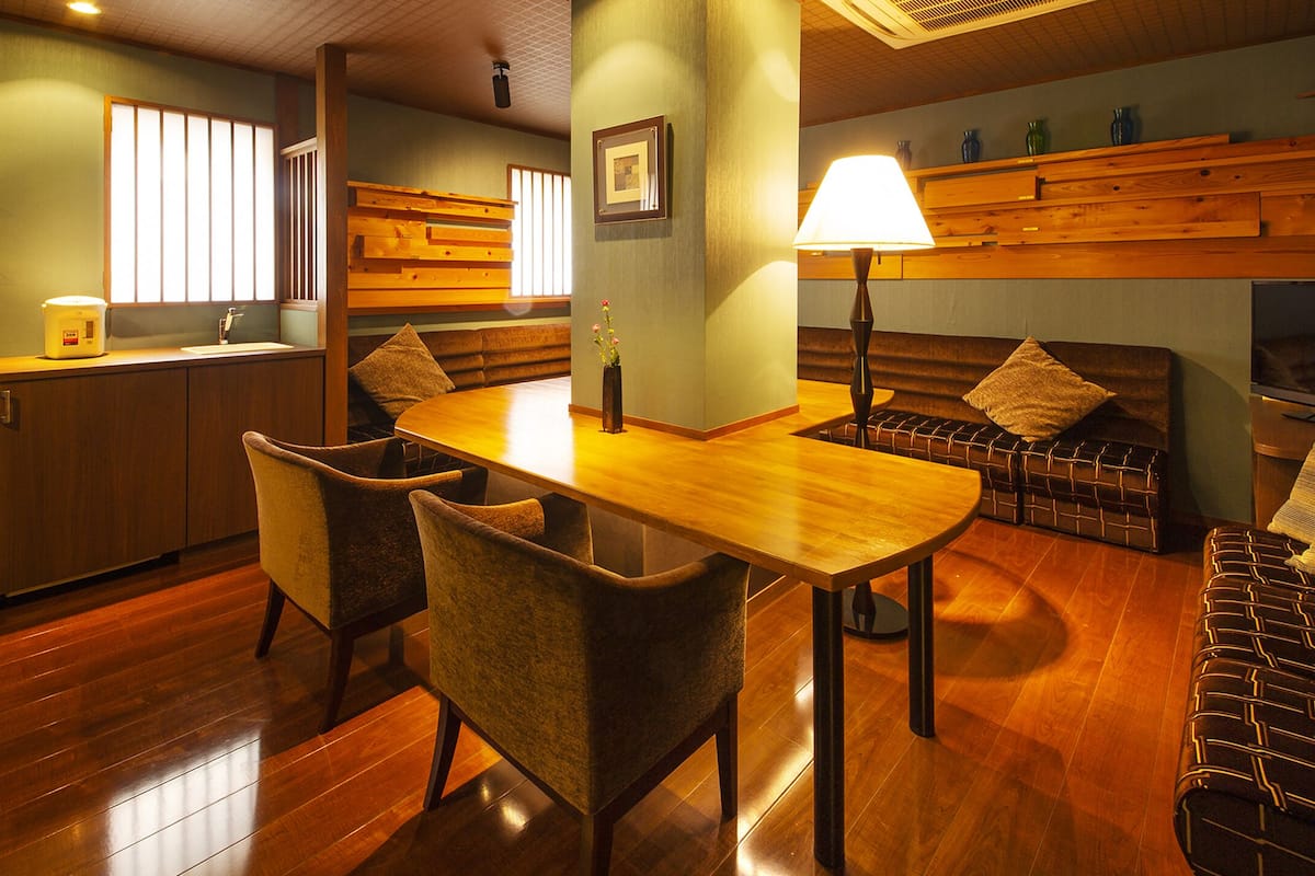 Una cocina moderna con armarios de madera, una mesa de comedor y sillas. Hay un sofá y una televisión en la sala de estar.