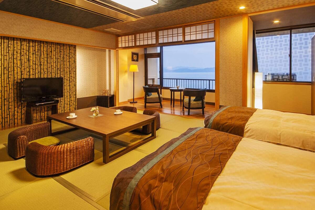 Habitación de hotel con una cama grande, una mesita pequeña, televisión y vista al mar.