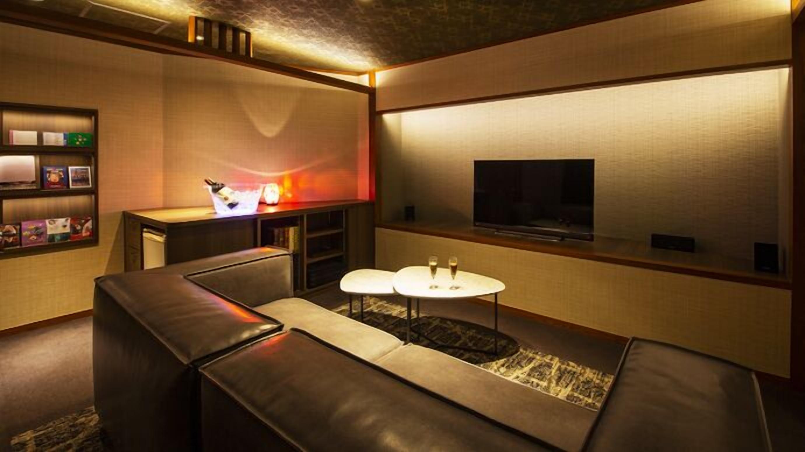 A modern living room with a sofa, a small coffee table, a flat-screen TV, and a bookshelf.