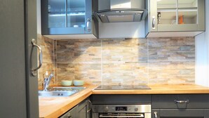 Een moderne keuken met een achterwand van steen, roestvrijstalen apparatuur en houten aanrechtbladen.