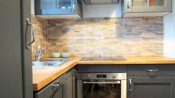 Une cuisine moderne avec un dosseret en pierre, des appareils en acier inoxydable et des plans de travail en bois.