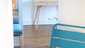 Een kamer met een houten vloer, een blauwe stoel, een houten bureau en een blauwe wand.