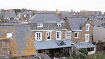 Un immeuble résidentiel doté d’une façade en pierre, de nombreuses fenêtres et d’un patio couvert.