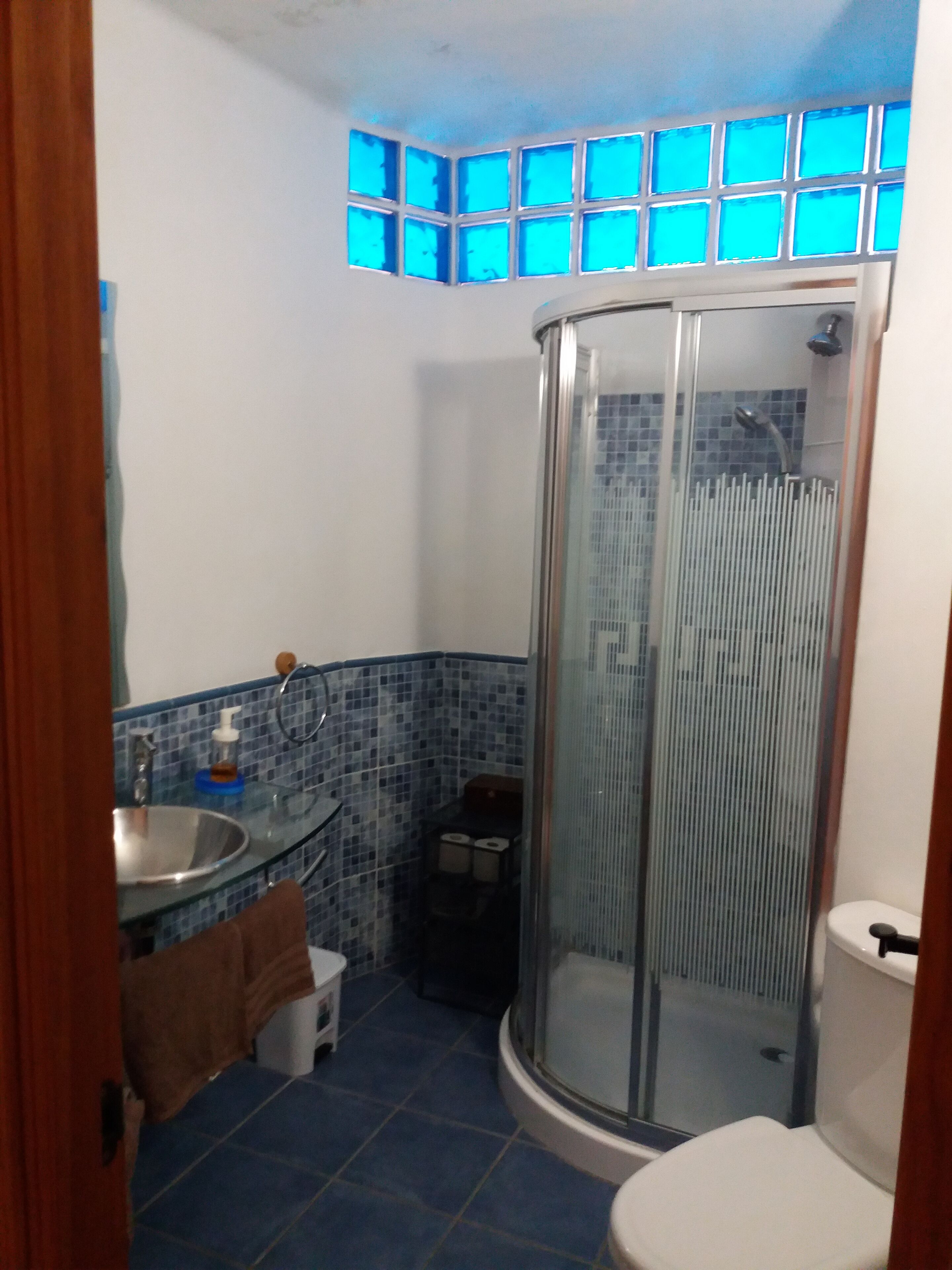 Een badkamer met een douchecabine van glas, een wastafel met spiegel en een toilet.