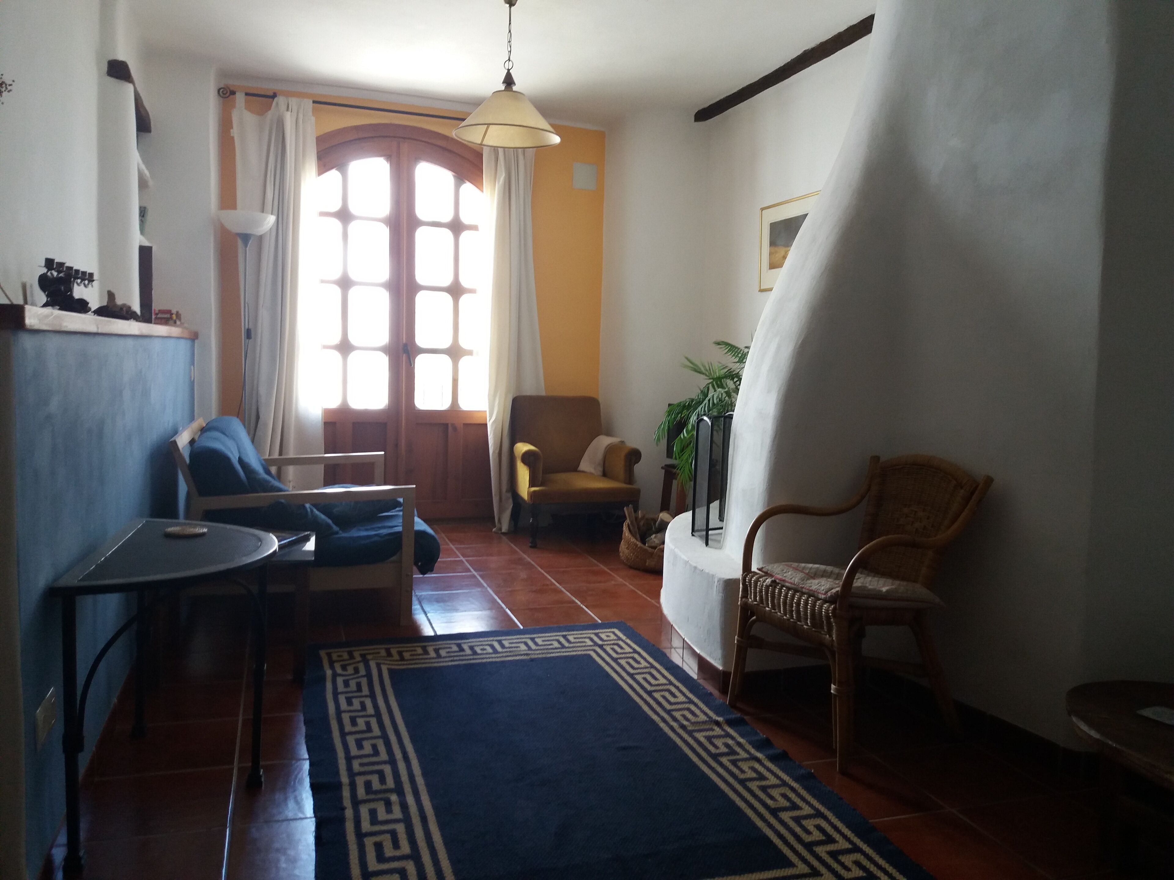 A cozy living room with a blue patterned rug, a wooden coffee table, a sofa, and two chairs.