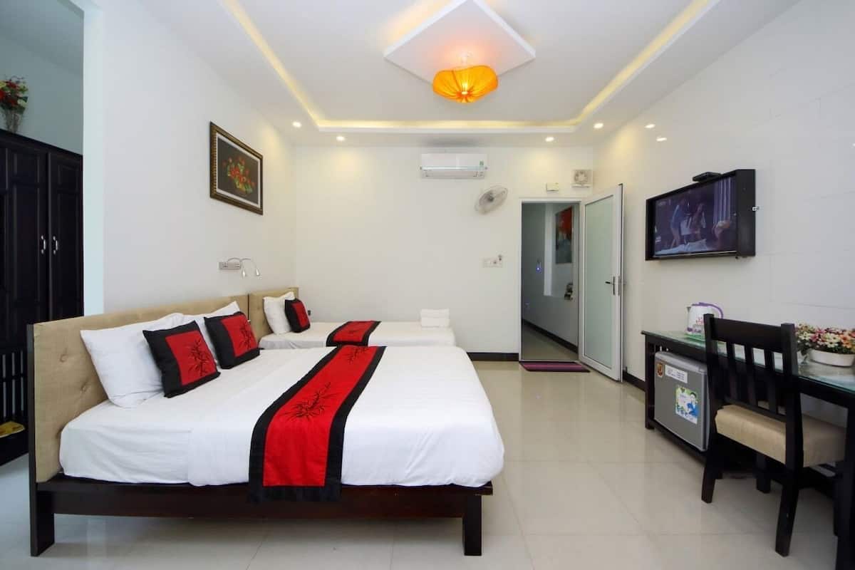 A hotel room with a bed, bedside table, TV, and a small desk with a chair.