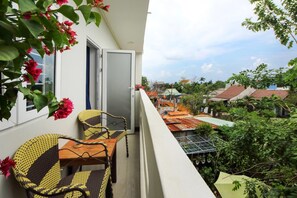 A balcony with wicker furniture and a view of a residential area with houses and greenery.