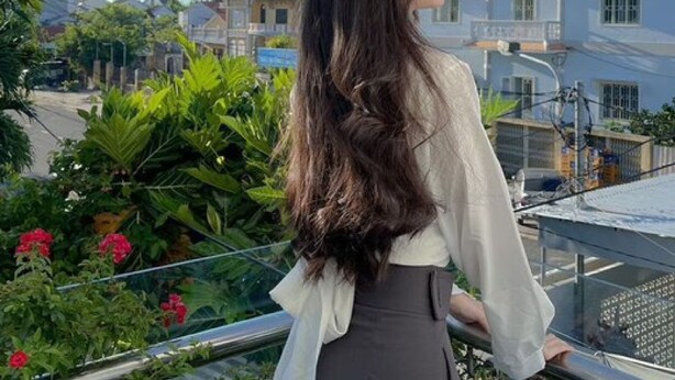 A person standing on a balcony overlooking a traditional pagoda-style building with multiple tiers. - Flame Flowers Homestay (Da Nang)