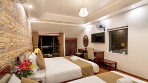 A hotel room with two beds, a desk, a chair, a TV, and a window with a view. - Flame Flowers Homestay (Da Nang)