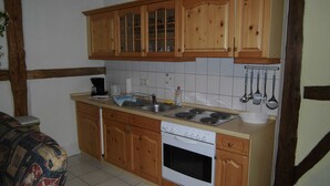 Une cuisine avec des meubles de rangement en bois, une cuisinière et un évier.