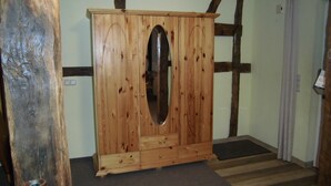 Une armoire en bois avec un miroir, un plancher en bois et une porte avec un rideau.