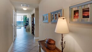 A hallway with a lamp, a wicker basket, and framed pictures on the wall. - 1105 - 2BR/2BA Coastal Gulf Views (Panama City Beach)