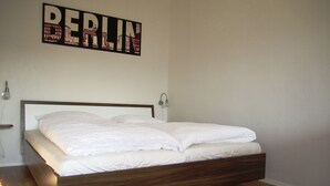 A modern bedroom with a wooden bed frame, white bedding, and a wall-mounted sign that reads "BERLIN". - Modern and quiet apartment right in the city center of Berlin (Berlin)