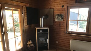 Interior de una cabaña de madera con chimenea, un ventanal grande y una alfombra de cuero de vaca.
