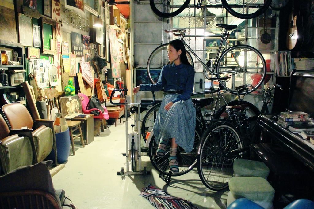Une pièce contenant un vélo, des chaises et divers objets disposés sur des étagères.