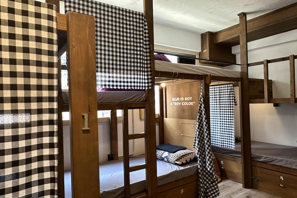 A bunk bed room with checkered bedding, a pegboard wall, and a message board stating "BLUE IS NOT A 'BOY COLOR'".
