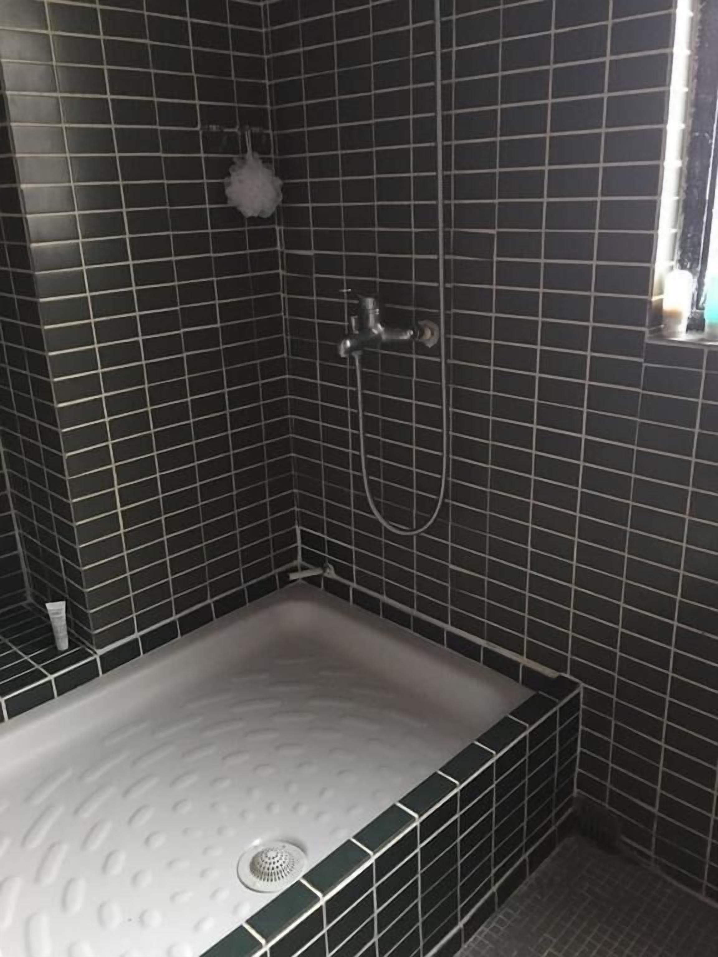 Un baño con bañera, paredes de azulejos y ducha.