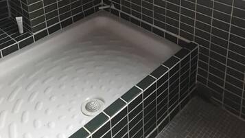 Un baño con bañera, paredes de azulejos y ducha.