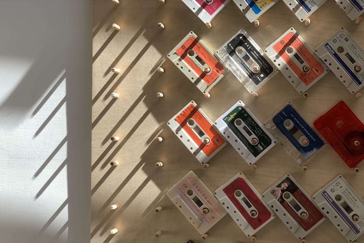 A wall with multiple cassette tapes arranged in rows, each secured with small wooden pegs.