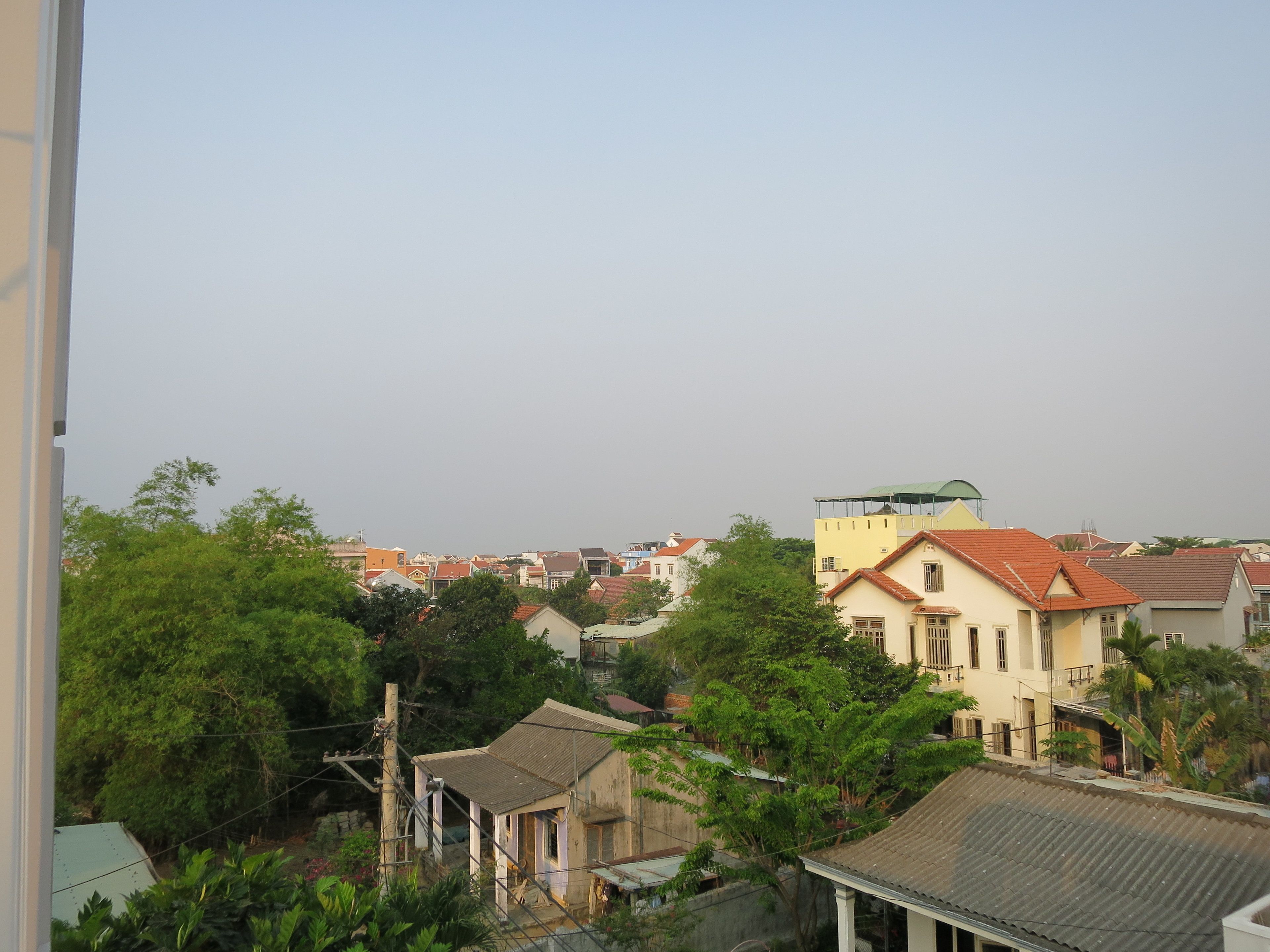 A residential area with houses, some with red roofs, and greenery.