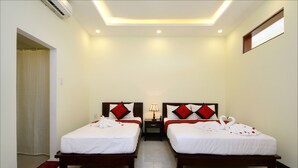 A hotel room with two beds, a nightstand, a lamp, and a window. - Fireworks Homestay (Da Nang)