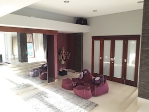 A modern living room with a glass partition, a large window, and a red door. - The Manipura Luxury Estate & SPA 730sqm Living Area, 20m Iinfinity Pool (Ubud)