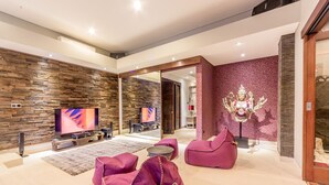A modern living room with a stone wall, a large flat-screen TV, and a statue of a deity. - The Manipura Luxury Estate & SPA 730sqm Living Area, 20m Iinfinity Pool (Ubud)
